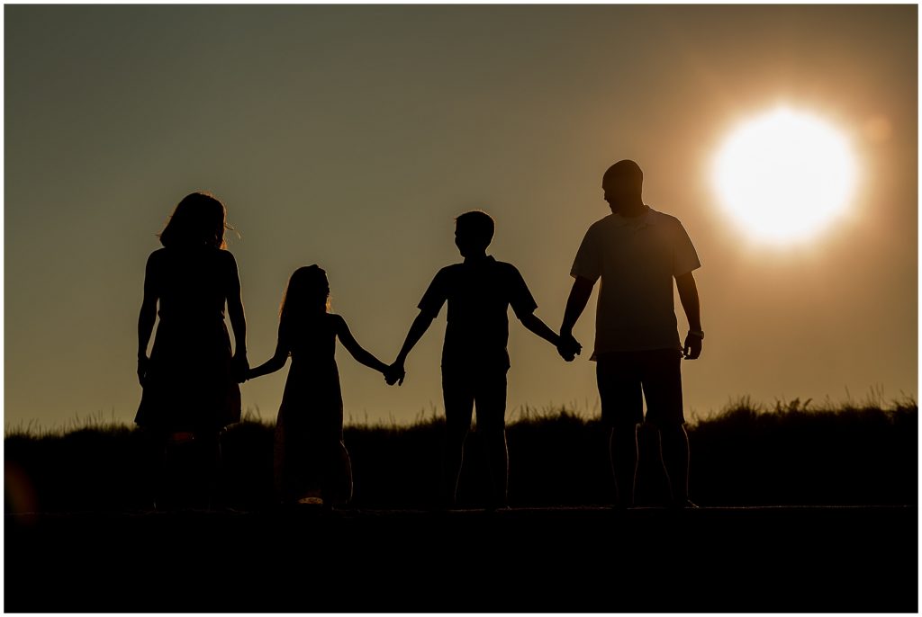 Silhouette of family at the beach with sun in the background