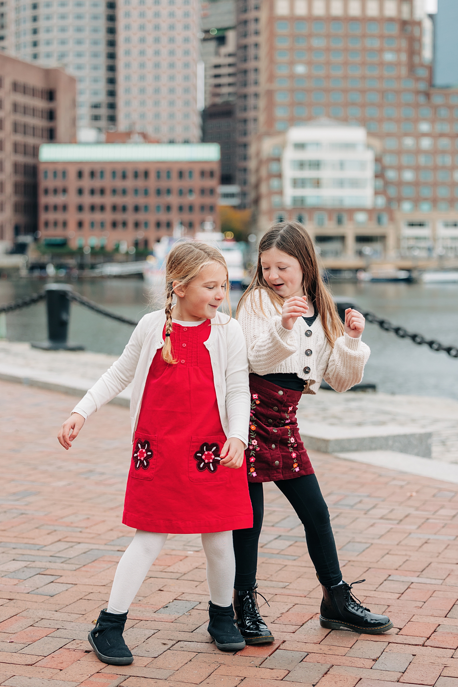 Two sisters bump hips in front of the Boston skyline