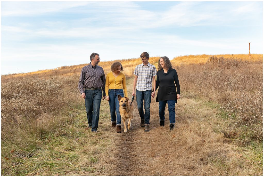 A family walks down a hill with their dog