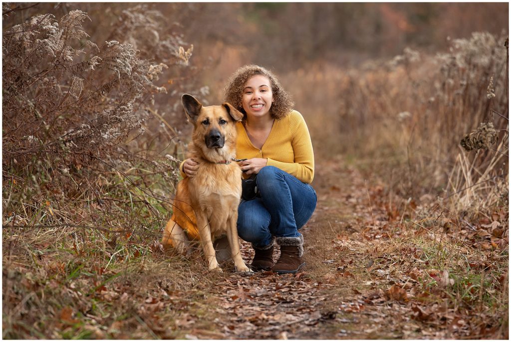 A teenage girl squats down next to her dog