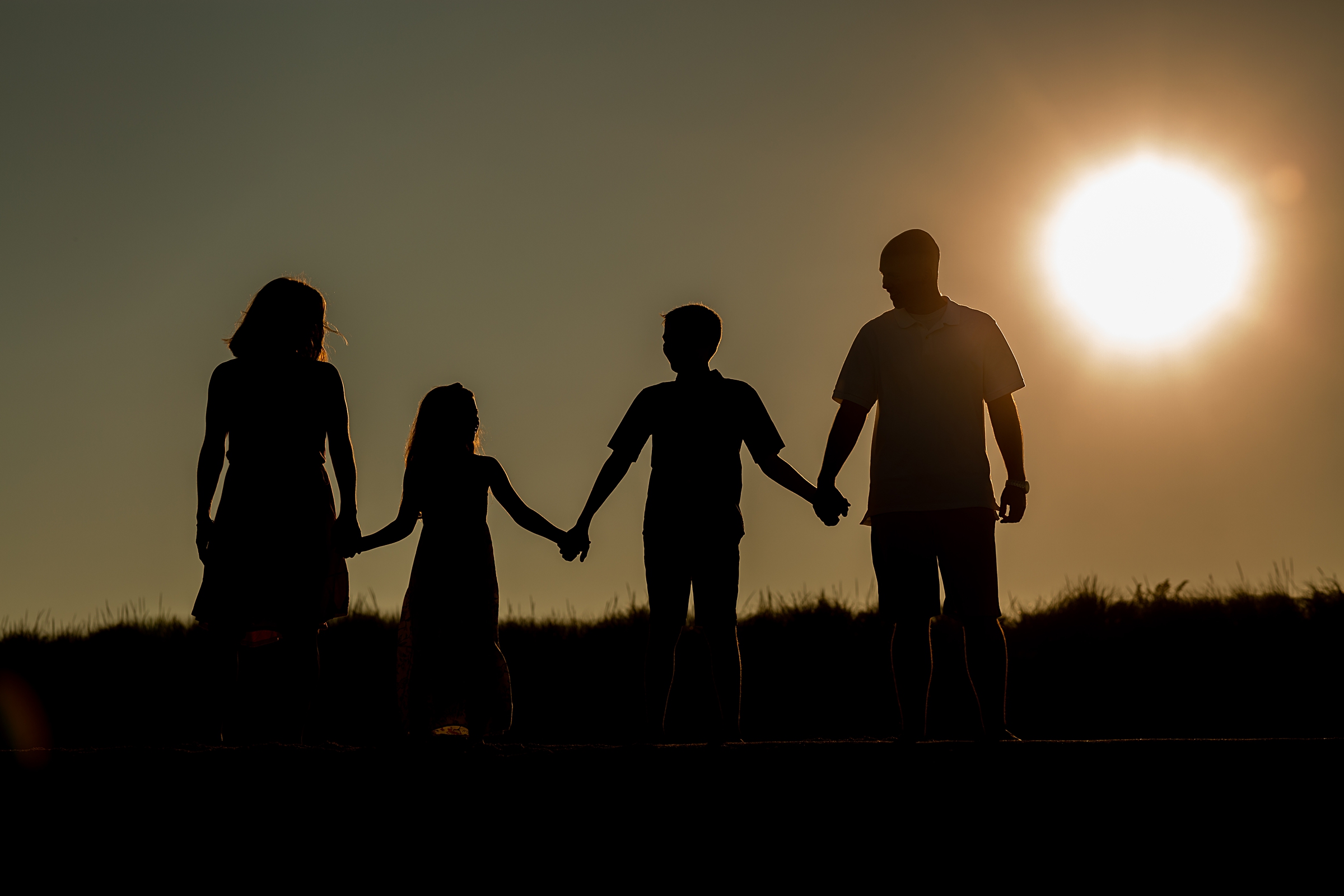 A family walks with the sun behind them