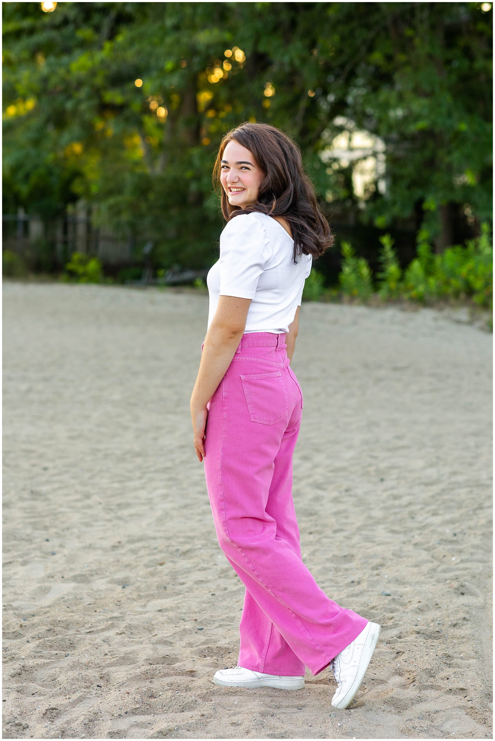 Girl in white shirt and pink pants dances in sand